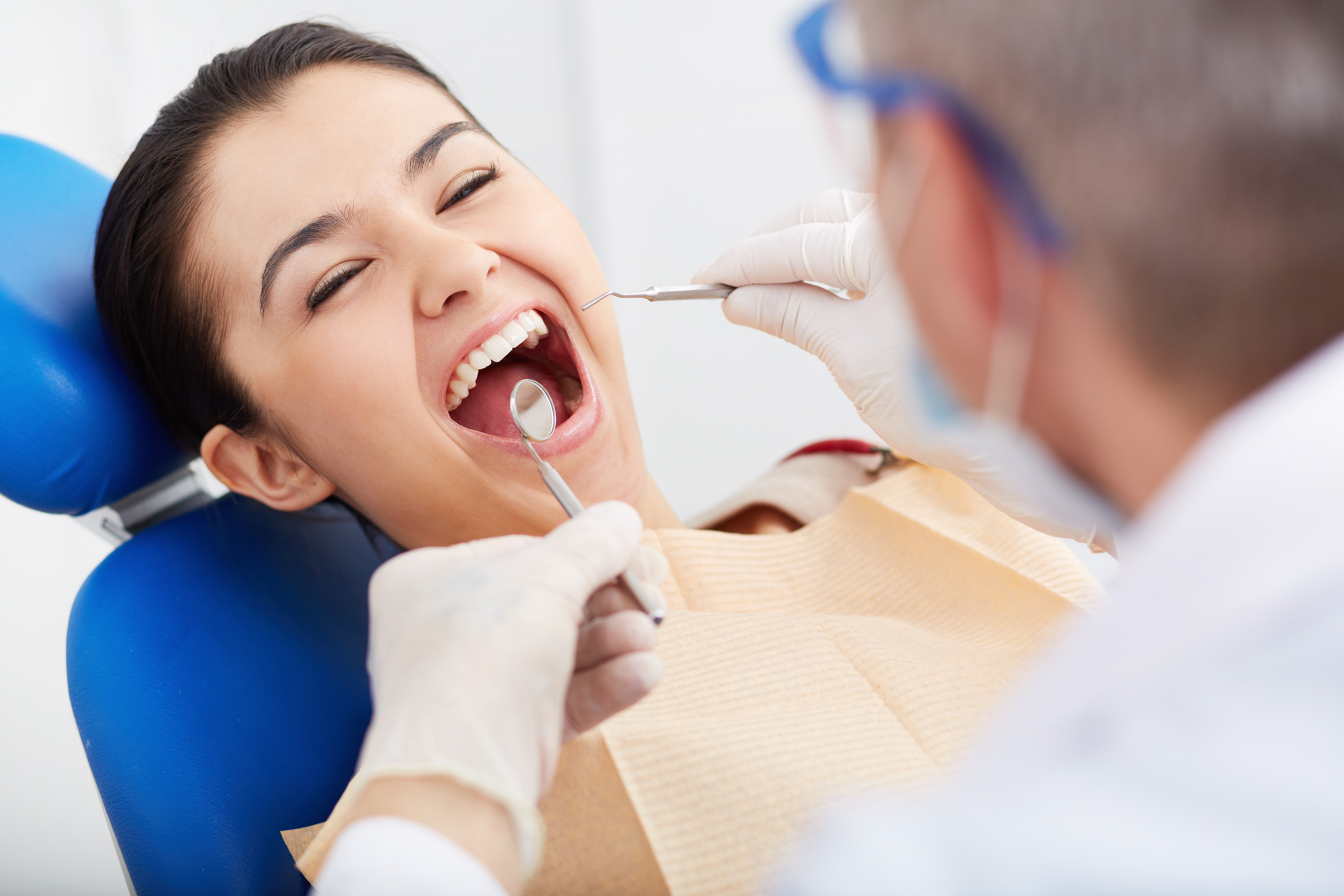 Close-up of girl with open mouth during oral checkup at the dentist’s